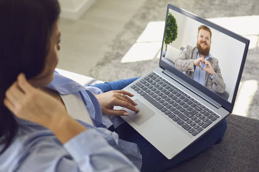 date online. loving couple. funny man looking at the camera smiling holds his hands in the shape of a heart video chat call using laptop at home.