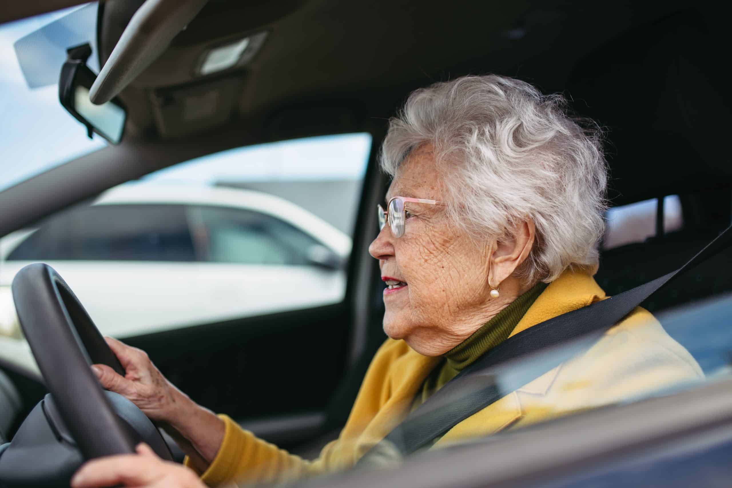 happy senior woman driving car alone, enjoying car ride. safe driving for elderly adults, older driver safety.