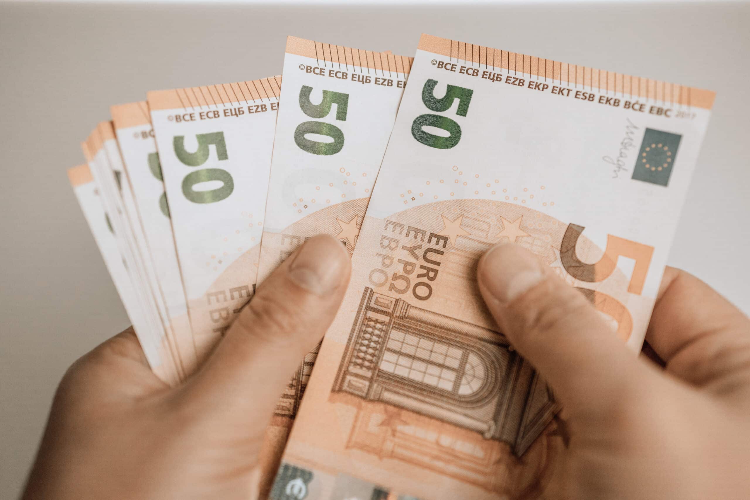 woman hands with euro money on grey background. saving money concept.